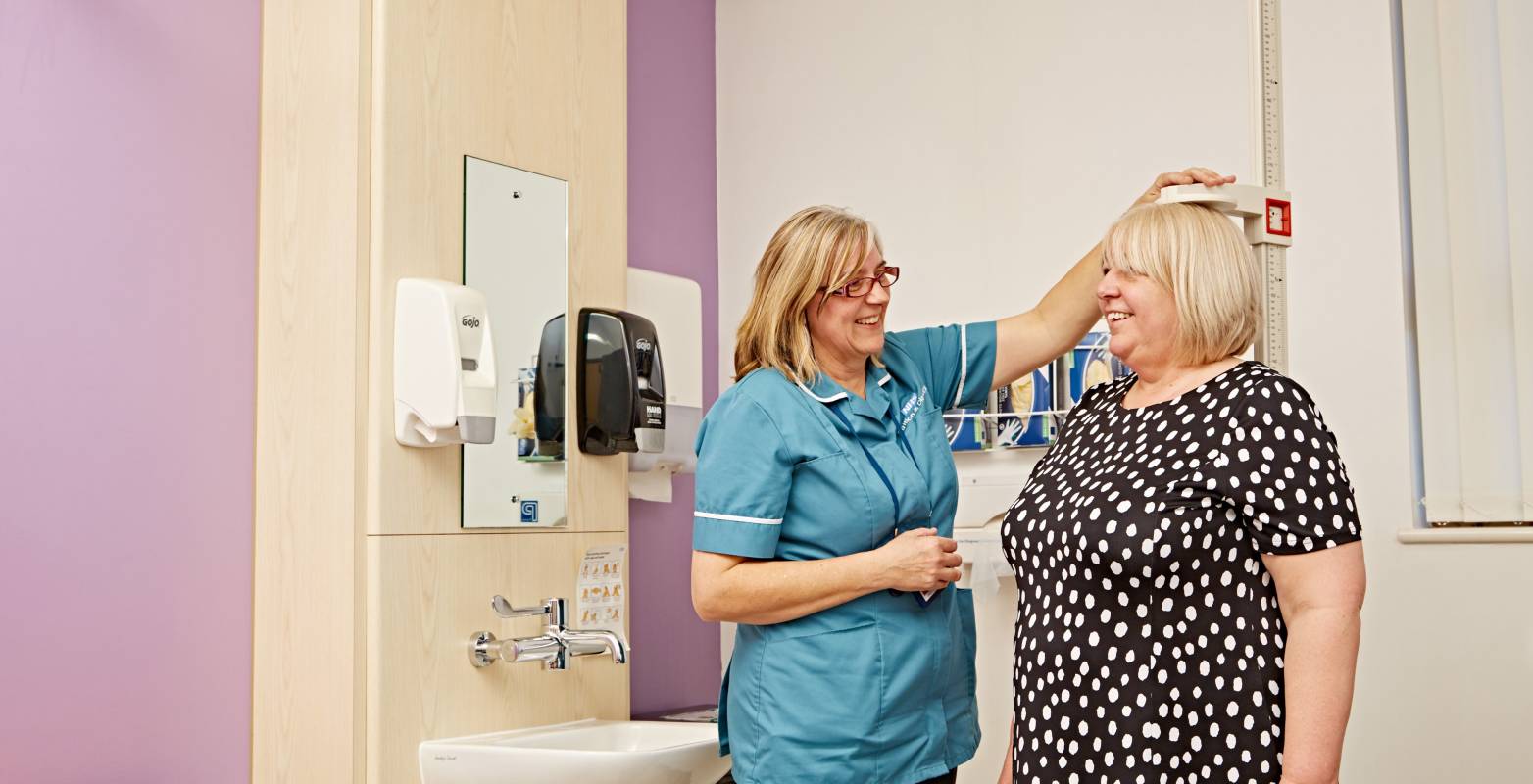 Hospital room with NHS key worker measuring patient height