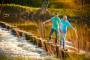 Thumbnail of couple walking hand-in-hand across river stepping stones